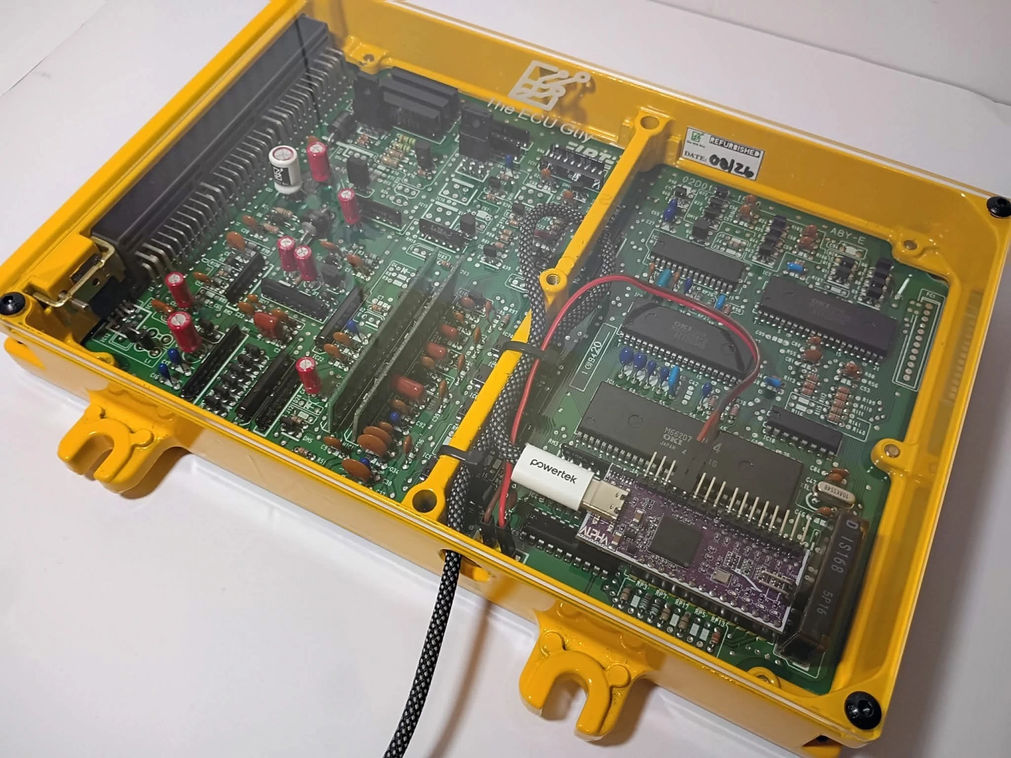 An ALPHA NextGEN emulator seated in a yellow The ECU Guy case, USB tuning cable connected